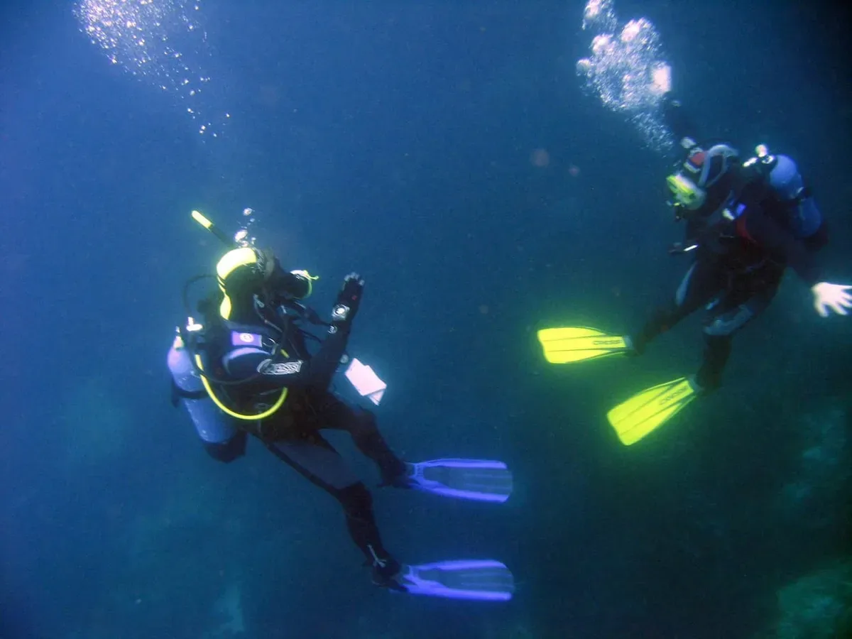 Professional diving instructor helping a guest with gear
