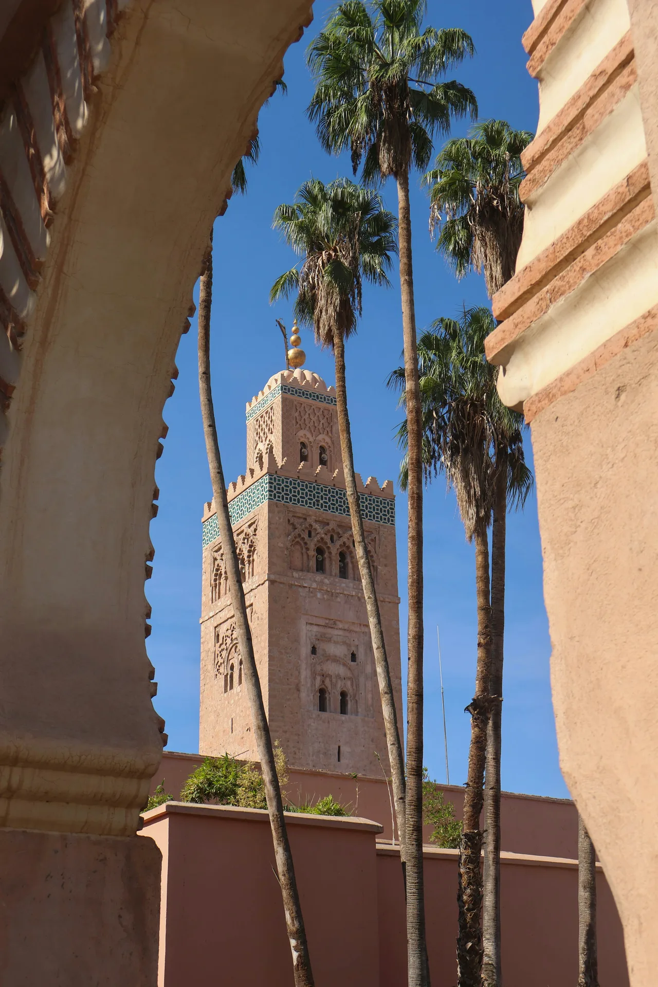Koutoubia Mosque minaret framed by palm trees and an arch in Marrakech